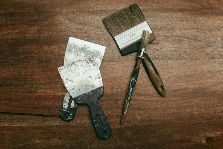 Brosse plate et spatule posées sur une planche de bois foncé