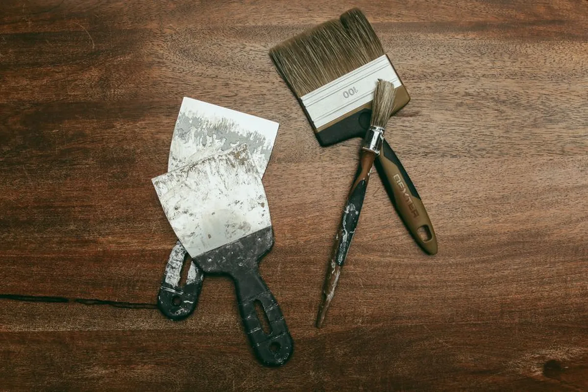 Brosse plate et spatule posées sur une planche de bois foncé