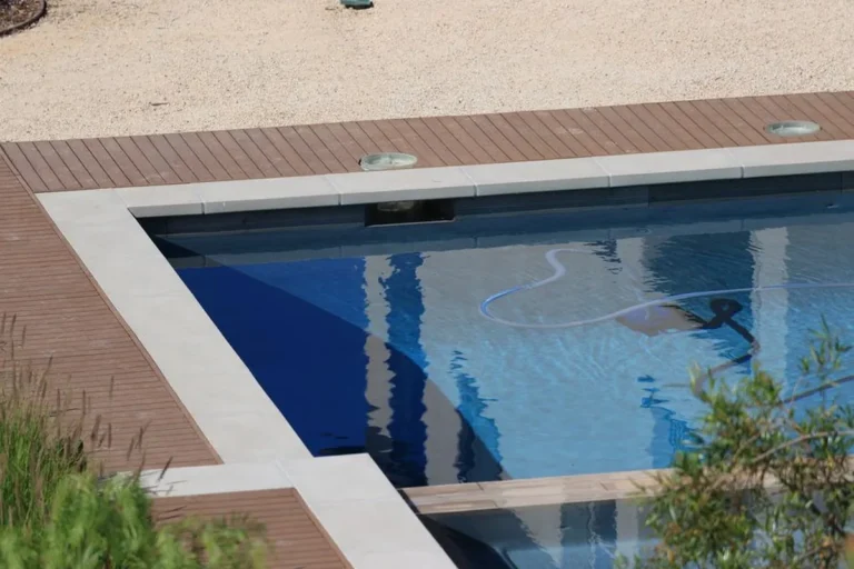 Terrasse en lames composite brunes exposée au soleil autour d'une piscine